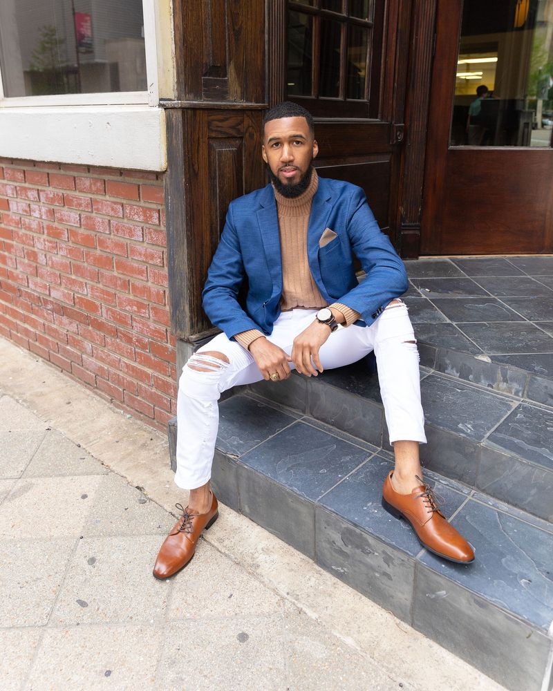 Jonathan Scott, founder of Visual Intelligence Co., sitting on the front steps of a brick building in a blue blazer.